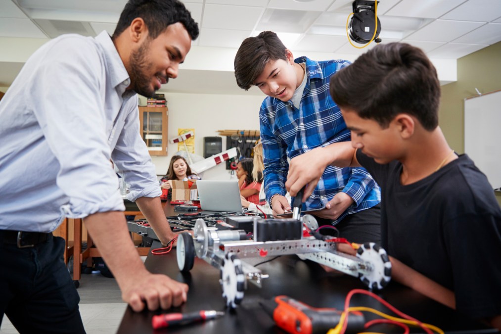 teacher with students working on robot