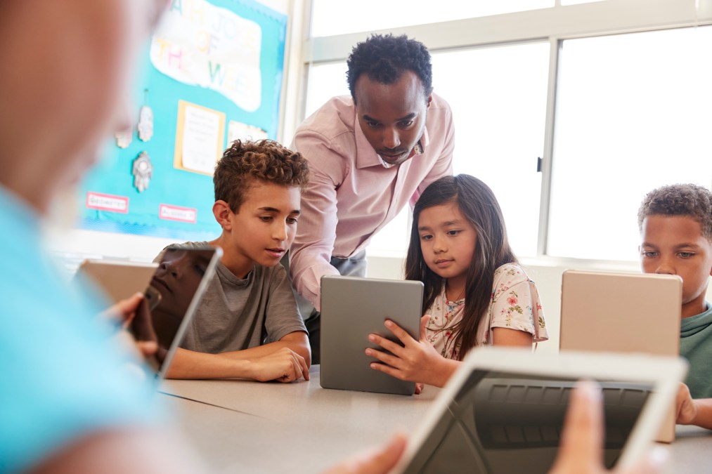 Teacher among school kids using computers in class