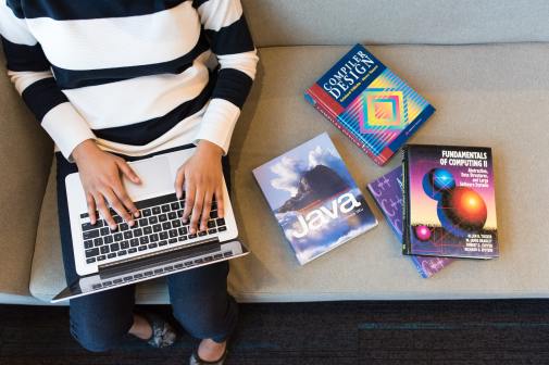 woman with laptop and coding textbooks