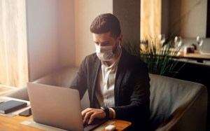 man wearing germ mask at laptop