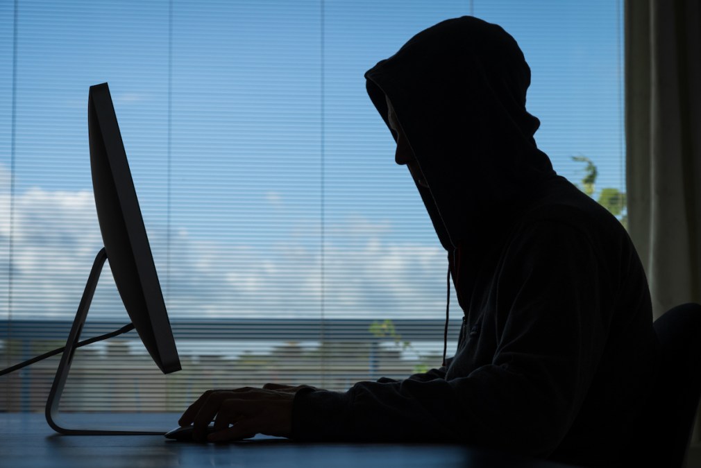 hooded figure in front of computer