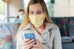 woman wearing mask using smartphone