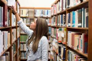 Young woman choosing book in library