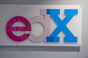 photograph of the edX logo mounted to the wall in colored perspex (the e is red, the d is clear, and the X is blue).
